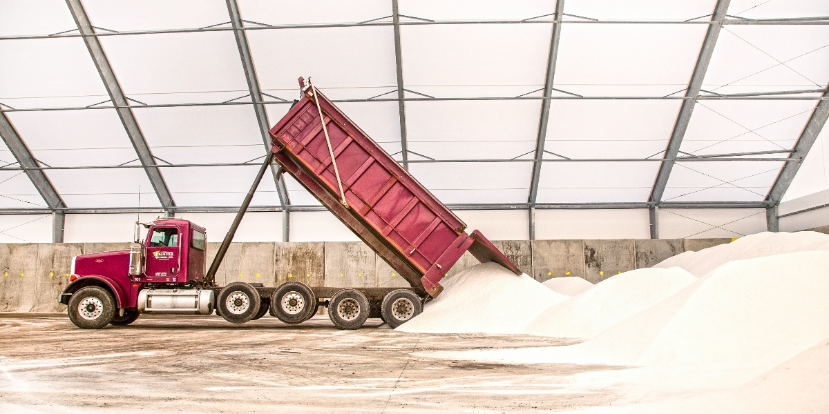 Photo of a truck dumping salt in a fabric storage building